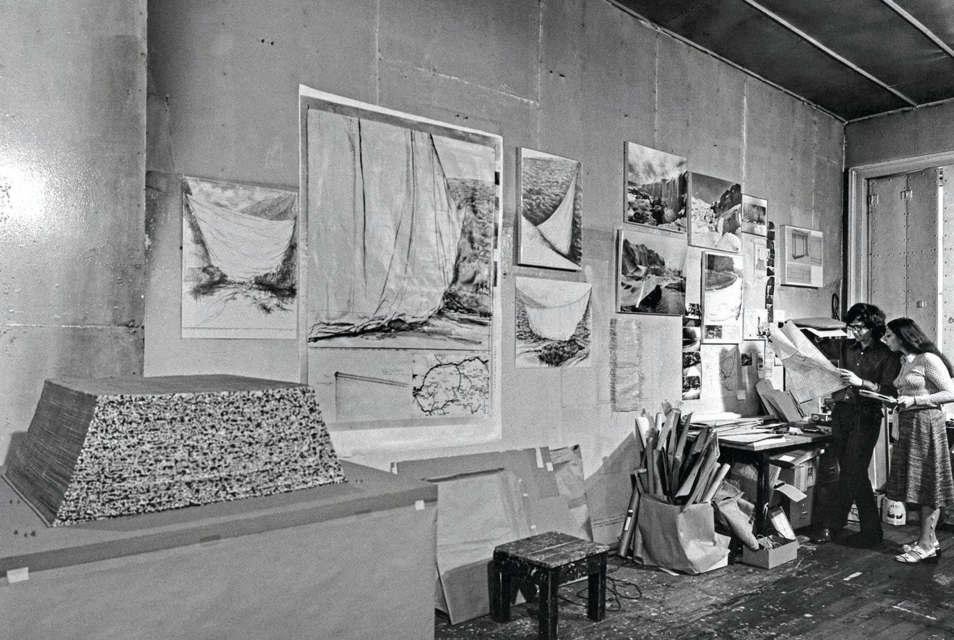 Christo and Jeanne-Claude in their studio with preparatory works for “Valley Curtain” in New York City in 1970. PHOTOGRAPHED BY WOLFGANG VOLZ & SHUNK-KENDER