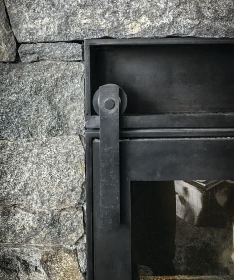 A detail of the steel-meets-stone sliding fireplace door. PHOTO COURTESY OF CCY ARCHITECTS